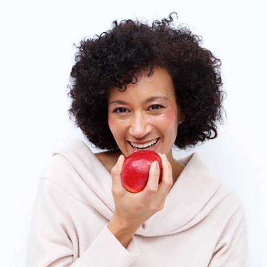 smiling woman taking a bite into a red apple