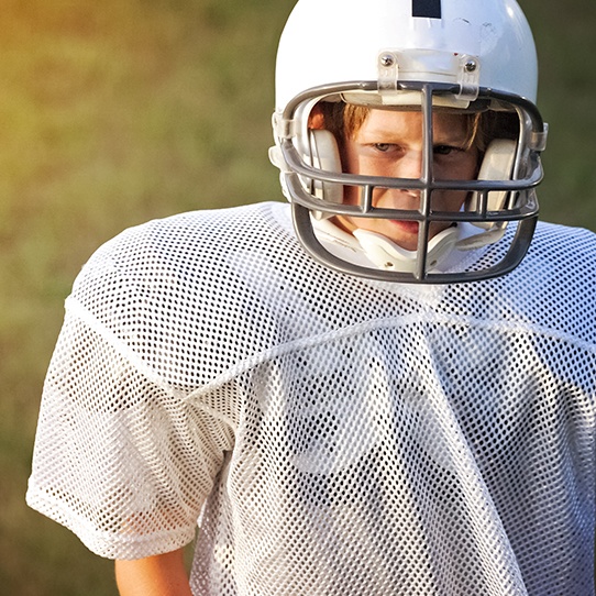 Teen boy wearing football helmet and athletic mouthguard